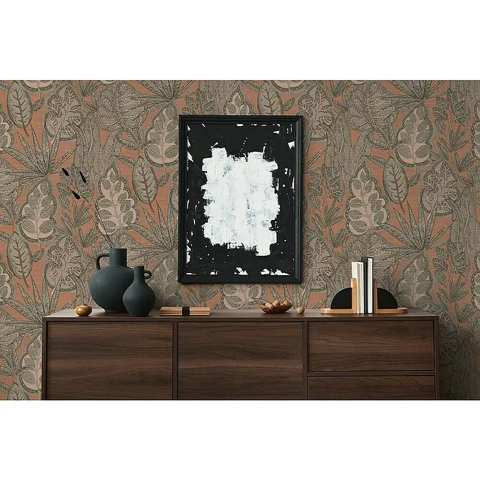 A.S. Création Famous Garden Vliestapete Blatt - Rosa-Grau-Taupe, Floral, 10,05 x 0,53 m - Blick auf ein modernes Sideboard aus Holz mit dekorativen Vasen, Büchern und einem abstrakten Kunstwerk an einer gemusterten Wand.
