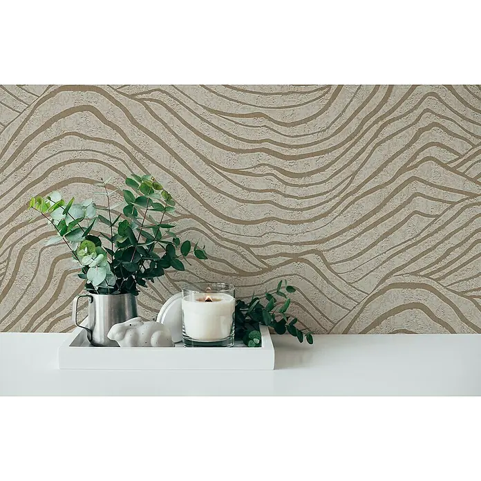 A.S. Création Jade 2 Vliestapete - Beige-Gold-Grau, 3D-Optik, 10,05 x 0,53 m - Stillleben mit Kerze, Eukalyptus und dekorativer Skulptur auf einem weißen Tablett vor gemusterter Wand.
