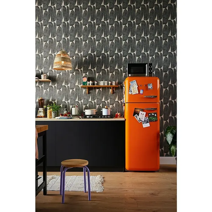 A.S. Création Stories of Life Vliestapete - Beige-Schwarz, Floral, 10,05 x 0,53 m - Küche mit einem auffälligen orangefarbenen Kühlschrank und einem stilvollen schwarzen Unterschrank unter einer hellen Arbeitsplatte.