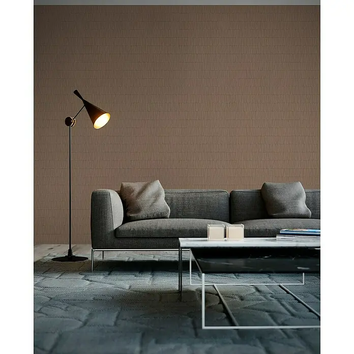 A.S. Création Jade 2 Vliestapete - Altrosa-Gold, Grafisch, 10,05 x 0,53 m - Wohnzimmer mit grauem Sofa, Couchtisch und Stehlampe. Die Wand hat ein subtiles geometrisches Muster, das dem Raum Tiefe verleiht.