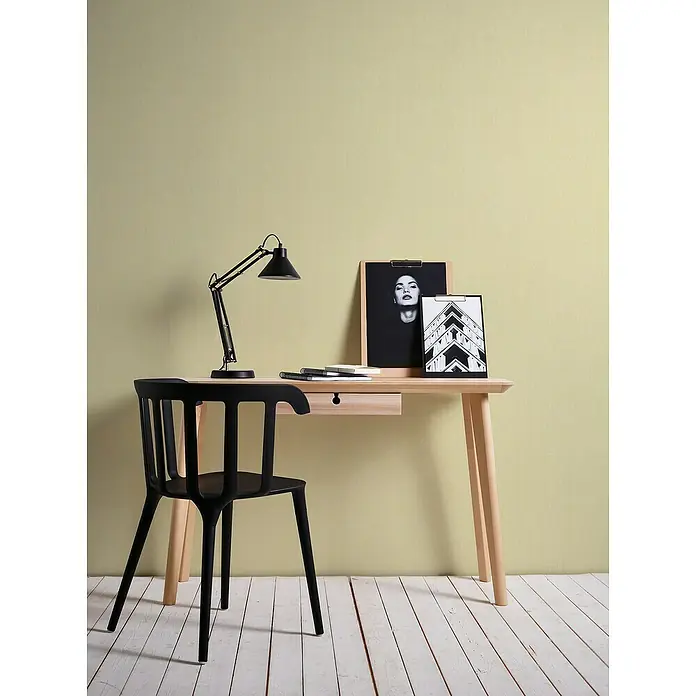 A.S. Création Stories of Life Vliestapete - Gelb-Grün, Uni, 10,05 x 0,53 m - Ein heller Holzschreibtisch mit einer Schublade, einer schwarzen Lampe und einem schwarzen Stuhl. Dekorative Bilder vervollständigen das Ensemble.