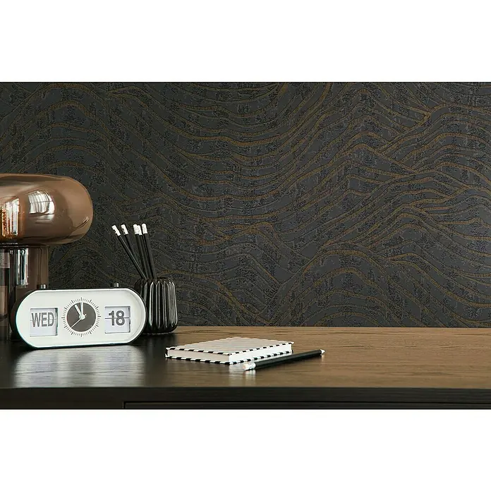 A.S. Création Jade 2 Vliestapete - Schwarz-Silber, 3D-Optik, 10,05 x 0,53 m - Nahaufnahme einer Arbeitsfläche mit einem Vintage-Flip-Uhr-Kalender, Stiften und einem Notizbuch, vor einer dunklen, strukturierten Wand.