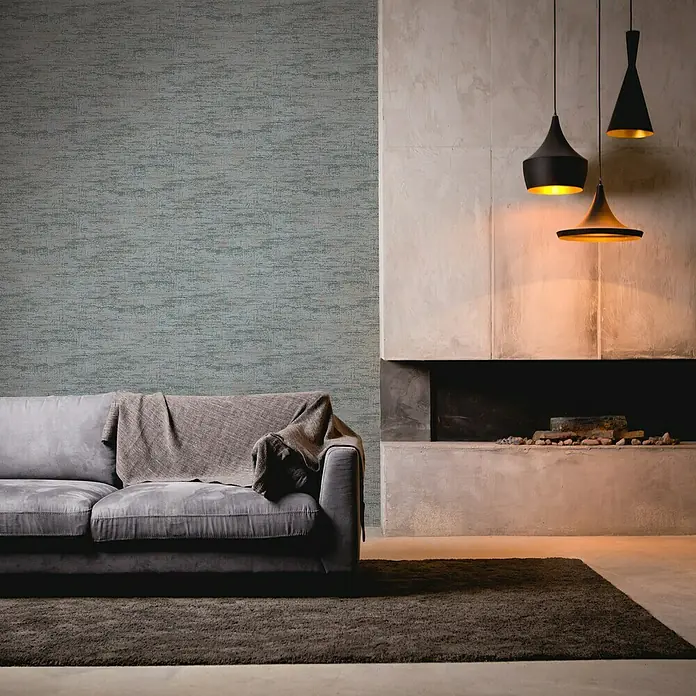 A.S. Création Stories of Life Vliestapete - Petrolgrün-Kupfer, Uni, 10,05 x 0,53 m - Elegantes Wohnzimmer mit einem grauen Sofa, einem dunklen Teppich und drei stilvollen Hängelampen, die warmes Licht spenden.