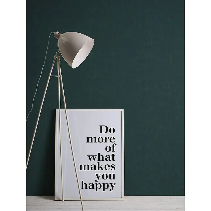 A.S. Création Jade 2 Vliestapete - Dunkles Petrol, Uni, 10,05 x 0,53 m - Stehlampe mit Schirm und ein gerahmtes Zitat "Do more of what makes you happy" vor einer dunkelgrünen Wand, die eine gemütliche Atmosphäre schaffen.