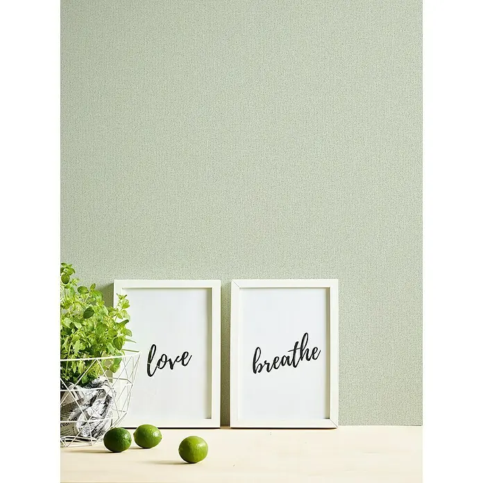 A.S. Création Jade 2 Vliestapete - Pastellgrün, Uni, 10,05 x 0,53 m - Nahaufnahme von zwei gerahmten Bildern mit den Aufschriften "Love" und "Breathe" sowie einer Topfpflanze und Limetten.