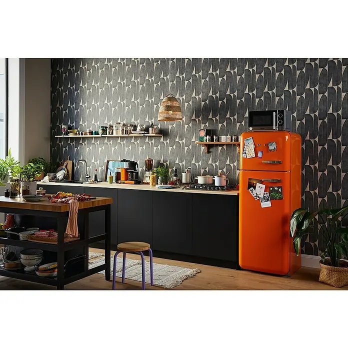 A.S. Création Stories of Life Vliestapete - Beige-Schwarz, Floral, 10,05 x 0,53 m - Küchenszene mit einem auffälligen, orangefarbenen Retro-Kühlschrank als Blickfang, ergänzt durch dunkle Schränke und einem Holztisch.