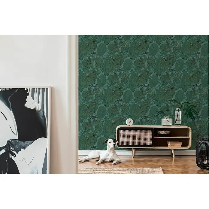 A.S. Création Famous Garden Vliestapete Dschungel - Petrol-Grün-Gold, Floral, 10,05 x 0,53 m - Eine grüne Tapete mit einem Pflanzenmuster im Wohnzimmer, ergänzt durch ein helles Holzmöbelstück und einen entspannten Hund.
