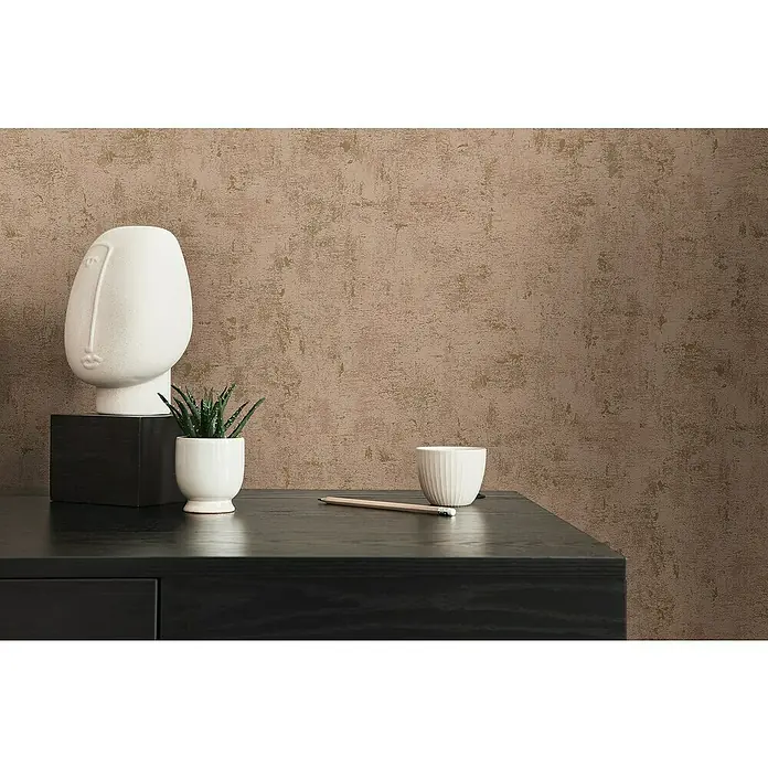 A.S. Création Jade 2 Vliestapete - Rosa-Gold, Uni, 10,05 x 0,53 m - Nahaufnahme einer modernen Wohnzimmerdekoration mit einer weißen Kopfskulptur, einer kleinen Pflanze, einer Tasse und einem Bleistift auf einem schwarzen Tisch.