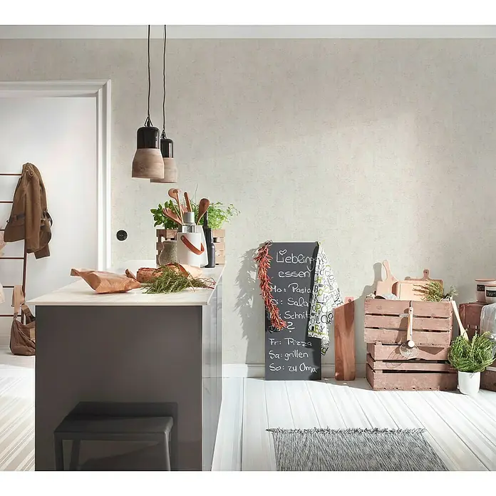 A.S. Création Jade 2 Vliestapete - Cremegrau, Uni, 10,05 x 0,53 m - Küchenszene mit einem Kreidetafel-Menü, frischen Kräutern und rustikalen Holzkisten, die eine gemütliche Atmosphäre schaffen.
