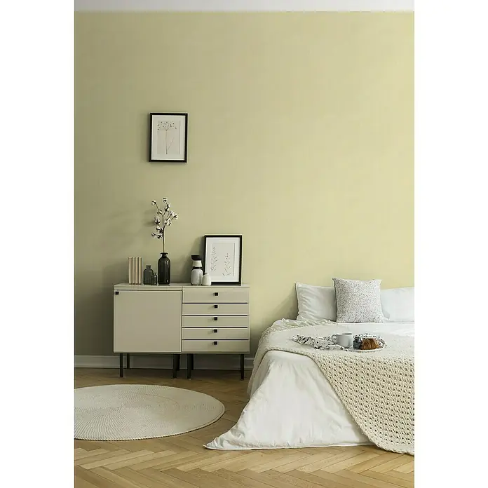 A.S. Création Stories of Life Vliestapete - Gelb-Grün, Uni, 10,05 x 0,53 m - Helles Schlafzimmer mit einem bequemen Bett mit weißer Bettwäsche und einer modernen Kommode mit Dekorationsgegenständen.