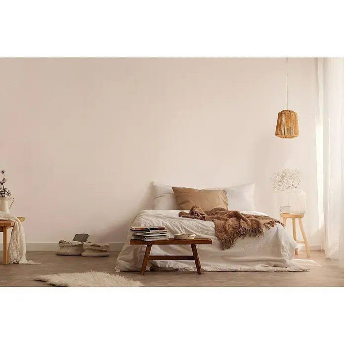 A.S. Création Jade 2 Vliestapete - Beige-Creme, Uni, 10,05 x 0,53 m - Stimmungsvolles Schlafzimmer mit bequemen Kissen, einer Strickdecke und einer Lampe, die ein warmes Licht verbreitet, für eine entspannte Atmosphäre.