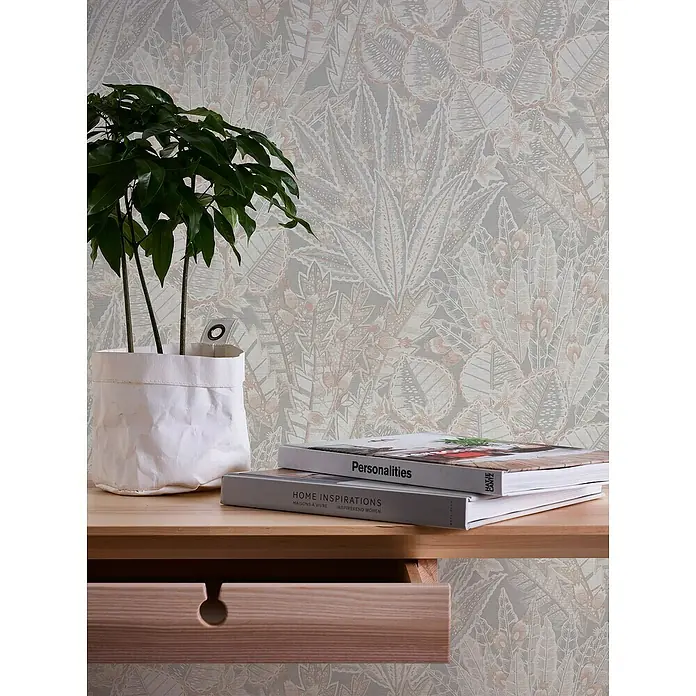 A.S. Création Stories of Life Vliestapete Blumen - Grau-Beige-Weiß, Floral, 10,05 x 0,53 m - Dekorative Nahaufnahme eines Tisches mit Pflanze, Büchern und einer Schublade vor einer stilvollen Blättertapete.