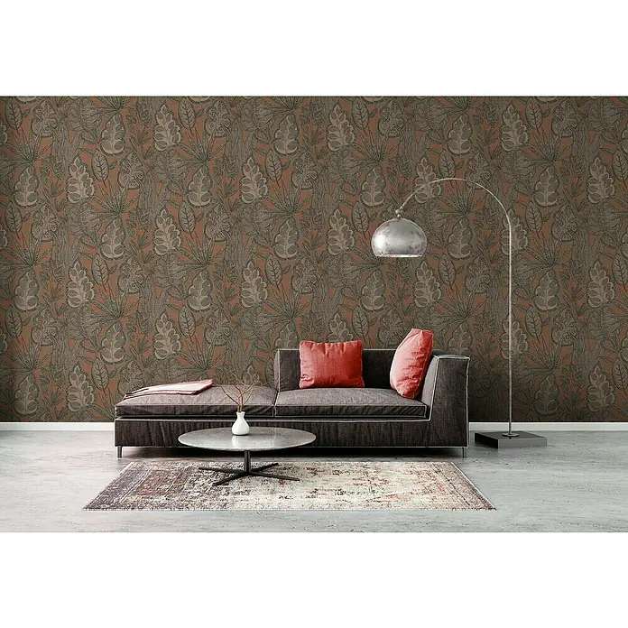 A.S. Création Famous Garden Vliestapete Blatt - Rosa-Grau-Taupe, Floral, 10,05 x 0,53 m - Zimmer mit gemusterter Tapete, modernem grauen Sofa mit roten Kissen, Couchtisch und Stehlampe für gemütliches Wohnen.