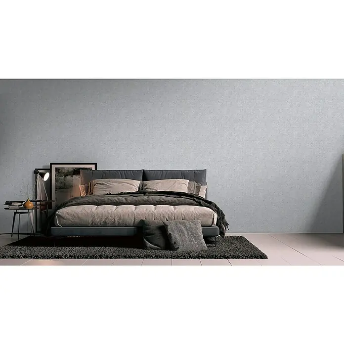 A.S. Création Stories of Life Vliestapete Used-Look - Hellgrau-Silber, Betonoptik, 10,05 x 0,53 m - Schlafzimmer mit einem Kingsize-Bett mit grauen Kissen und einer Decke auf einem dunklen Teppich. Ein bequemes und stilvolles Bett für erholsame Nächte.