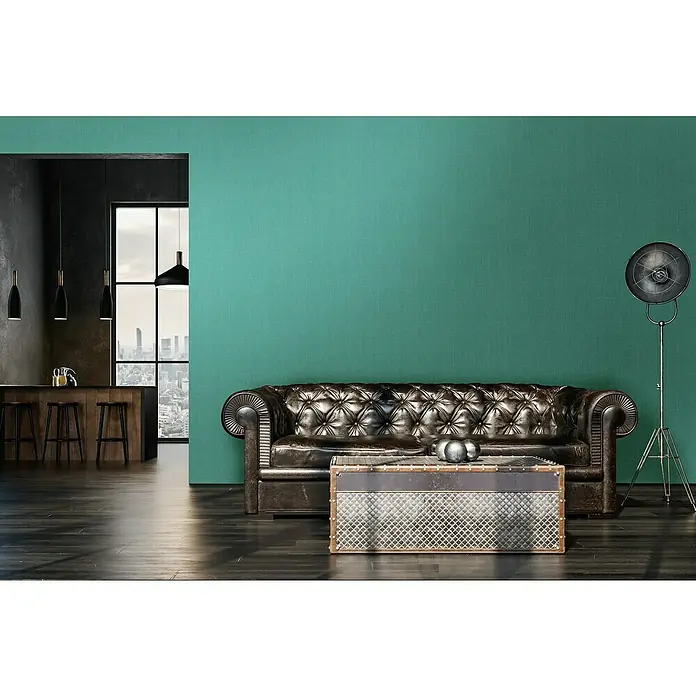 A.S. Création Stories of Life Vliestapete - Smaragdgrün, Uni, 10,05 x 0,53 m - Ein luxuriöses Wohnzimmer mit einem stilvollen braunen Ledersofa und einem einzigartigen Couchtisch in einem modernen Loft-Apartment.