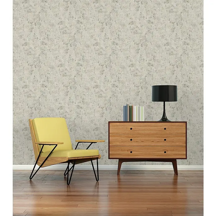 A.S. Création Jade 2 Vliestapete - Weiß-Taupe-Rosa, Uni, 10,05 x 0,53 m - Gelber Sessel mit Holzkommode, Lampe und Büchern vor einer gemusterten Wand.