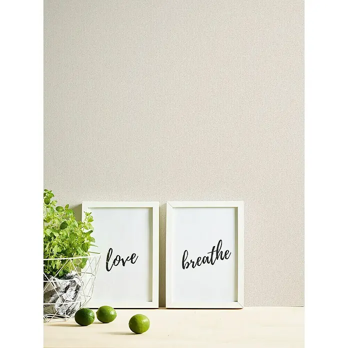 A.S. Création Jade 2 Vliestapete - Creme-Weiß, Uni, 10,05 x 0,53 m - Nahaufnahme zweier gerahmter Kunstdrucke mit den Worten "love" und "breathe", begleitet von einer Pflanze und Limetten für ein ruhiges Ambiente.