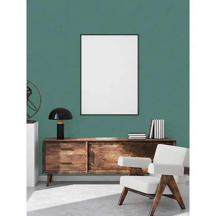 A.S. Création Famous Garden Vliestapete - Petrol-Grün, Uni, 10,05 x 0,53 m - Ein stilvolles Interieur mit einem Holzschrank, einer Lampe und einem gerahmten Bild, das eine ruhige und moderne Atmosphäre schafft.