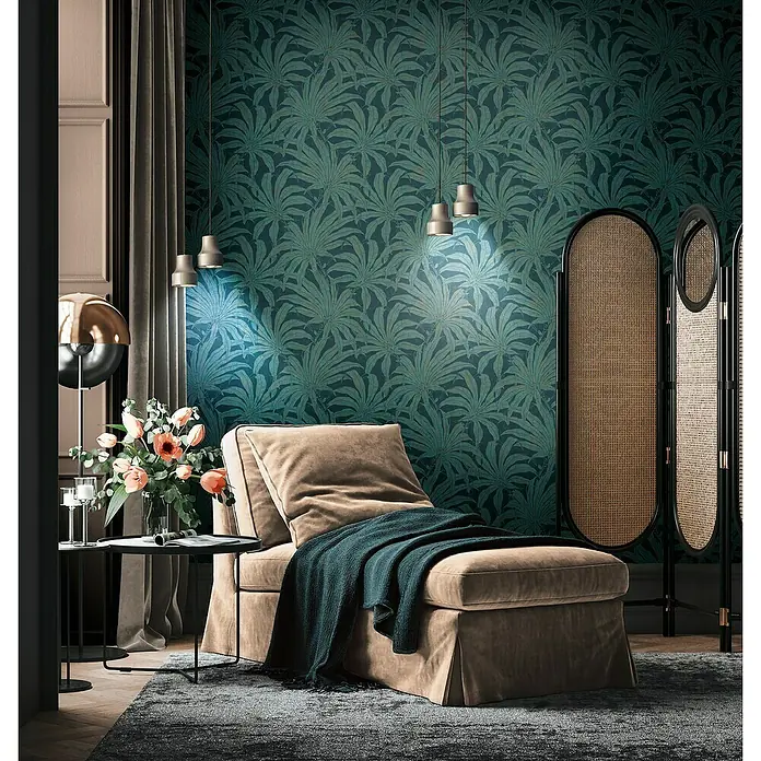 A.S. Création Jade 2 Vliestapete Pflanzen - Petrol-Gold-Blau, Floral, 10,05 x 0,53 m - Ein gemütlicher Lesesessel mit Überwurfdecke und Beistelltisch vor einer Wand mit botanischem Muster, beleuchtet von eleganten Pendelleuchten.