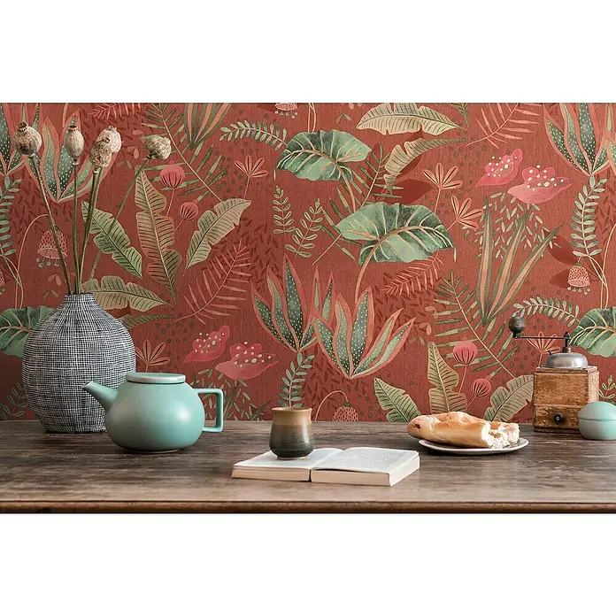 A.S. Création Famous Garden Vliestapete - Rot-Orange-Grün, Floral, 10,05 x 0,53 m - Stillleben mit Teekanne, Buch und Brot auf einem Holztisch vor einer floralen Tapete.