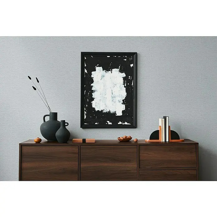 A.S. Création Famous Garden Vliestapete - Grau-Hellgrau, Uni, 10,05 x 0,53 m - Ein modernes Interieur mit einem dunklen Holzsideboard, dekoriert mit Vasen, einem abstrakten Gemälde und Buchstützen.