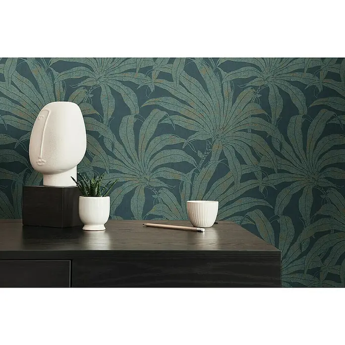 A.S. Création Jade 2 Vliestapete Pflanzen - Petrol-Gold-Blau, Floral, 10,05 x 0,53 m - Nahaufnahme eines schwarzen Tisches mit einer modernen Skulptur, einer Sukkulente, einer Tasse und einem Bleistift vor einer grünen Tapete.