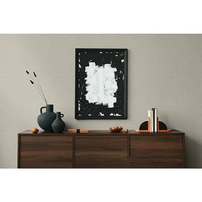 A.S. Création Famous Garden Vliestapete - Taupe, Uni, 10,05 x 0,53 m - Nahaufnahme eines stilvollen Sideboards aus dunklem Holz mit Dekorationsgegenständen und einem gerahmten, abstrakten Kunstwerk an der Wand.