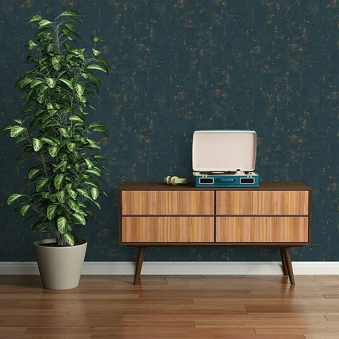 A.S. Création Jade 2 Vliestapete - Dunkelblau-Gold, Uni, 10,05 x 0,53 m - Ein elegantes Interieur mit einer grünen Zimmerpflanze und einem blauen Plattenspieler auf einem Holzschrank vor einer dunklen Wand.