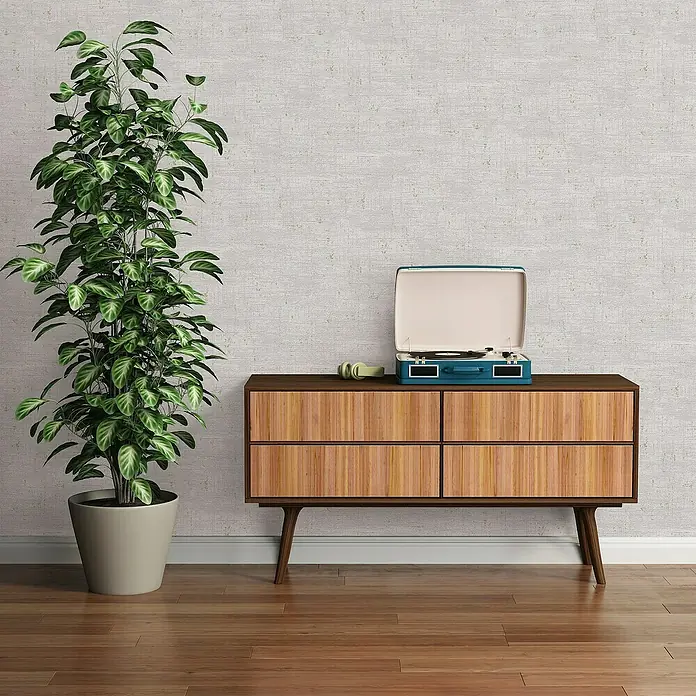 A.S. Création Stories of Life Vliestapete - Grau-Creme-Gold, Uni, 10,05 x 0,53 m - Elegantes Interieur mit einem Plattenspieler auf einer Holzkommode, neben einer Zimmerpflanze, die eine stilvolle Atmosphäre schafft.