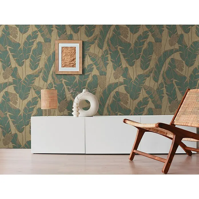 A.S. Création Jade 2 Vliestapete Blätter - Beige-Grün-Schwarz, Floral, 10,05 x 0,53 m - Wohnzimmer mit einem modernen TV-Schrank in Weiß, einem Holzstuhl und einer Wand mit auffälligem Blattmuster-Tapete.