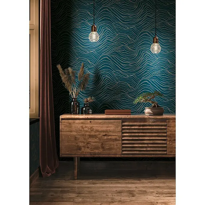 A.S. Création Jade 2 Vliestapete - Dunkelblau-Gold, 3D-Optik, 10,05 x 0,53 m - Wohnzimmer-Interieur mit einem hölzernen Sideboard, dekoriert mit Vasen, Büchern und einer Bonsai-Pflanze, unter zwei Pendelleuchten.