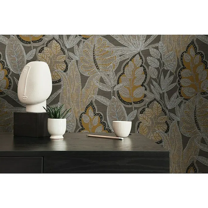 A.S. Création Famous Garden Vliestapete Blatt - Braun-Orange-Weiß, Floral, 10,05 x 0,53 m - Aufnahme eines Tisches mit Dekoartikeln, darunter eine moderne Skulptur, Topfpflanze und eine kleine Schale vor einem Hintergrund mit floralem Muster.
