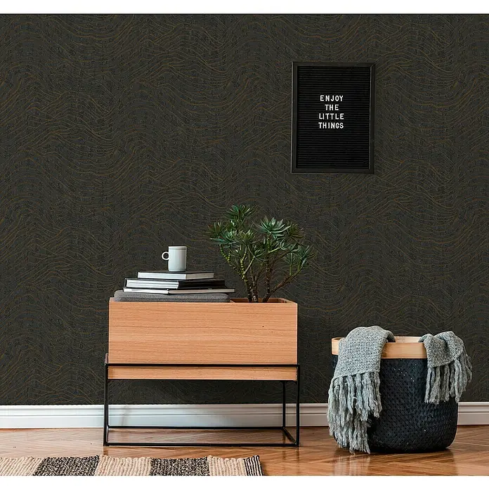 A.S. Création Jade 2 Vliestapete - Schwarz-Silber, 3D-Optik, 10,05 x 0,53 m - Einrichten mit dunkler, gewellter Tapete, einem Holzschrank mit Pflanze, Büchern und Tasse, sowie einem Korb mit Decke.