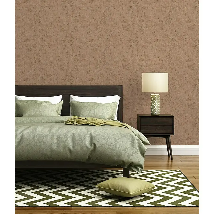 A.S. Création Jade 2 Vliestapete - Rosa-Gold, Uni, 10,05 x 0,53 m - Schlafzimmer mit Doppelbett, Nachttischlampe und Teppich mit Zickzackmuster in Grün- und Weißtönen.