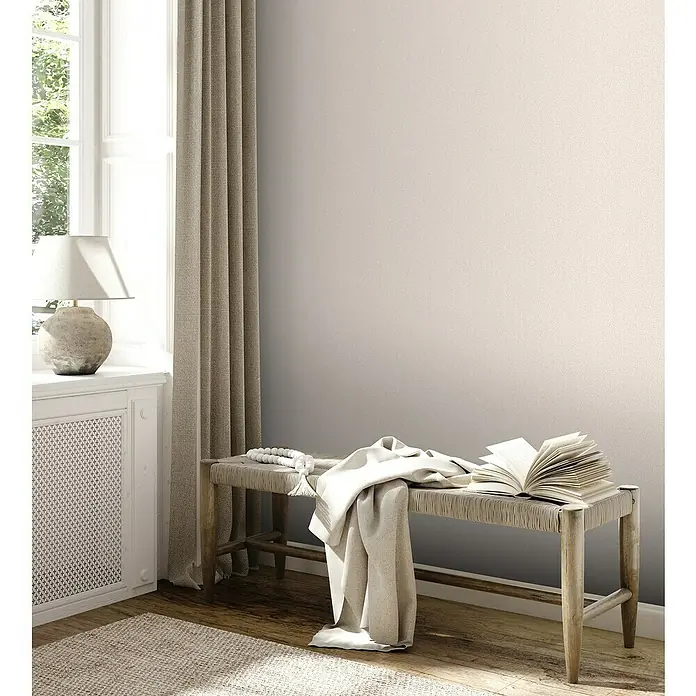A.S. Création Jade 2 Vliestapete - Beige-Creme, Uni, 10,05 x 0,53 m - Einladende Szene mit einer hellen Bank, einem aufgeschlagenen Buch und einer weichen Decke, die zum Verweilen einlädt.