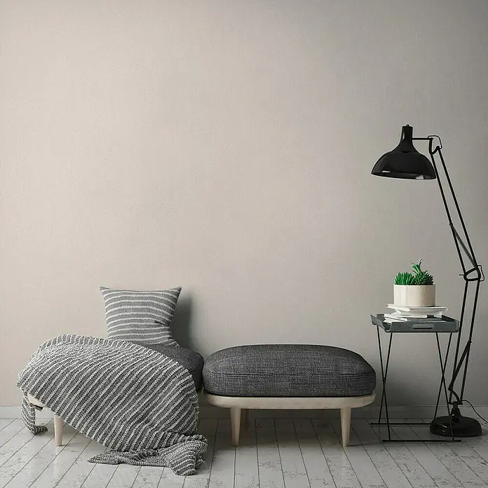 A.S. Création Jade 2 Vliestapete - Beige-Creme, Uni, 10,05 x 0,53 m - Wohnzimmer-Szene mit einem schwarzen Bogenlampe neben einem Beistelltisch mit Pflanze, einem Hocker und einem Sessel mit Decke.