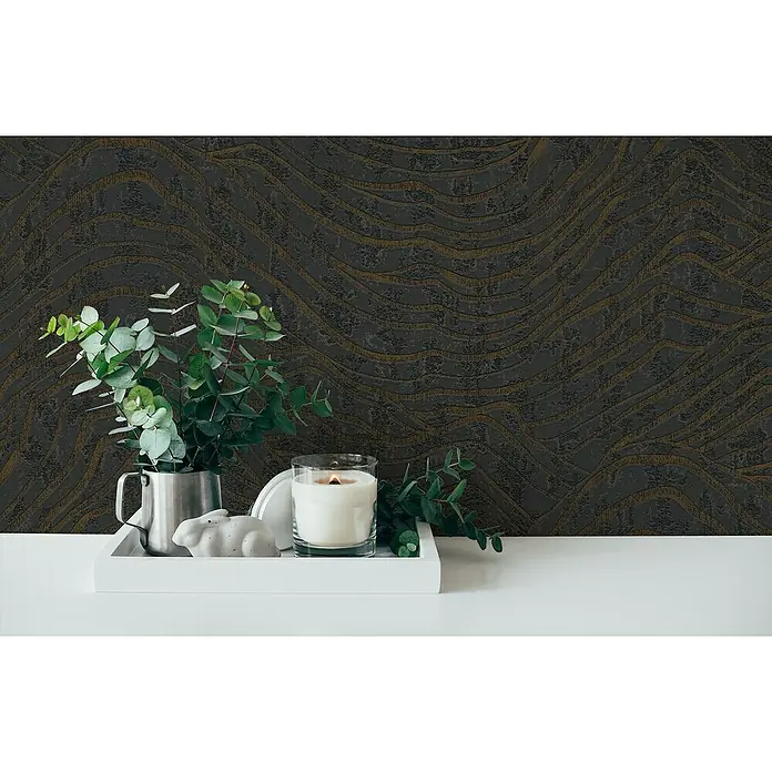 A.S. Création Jade 2 Vliestapete - Schwarz-Silber, 3D-Optik, 10,05 x 0,53 m - Dekorative Stillleben-Szene mit einer Kerze, einer Pflanze und einer Kaninchenfigur auf einem weißen Tablett, vor einer strukturierten, dunklen Wand.