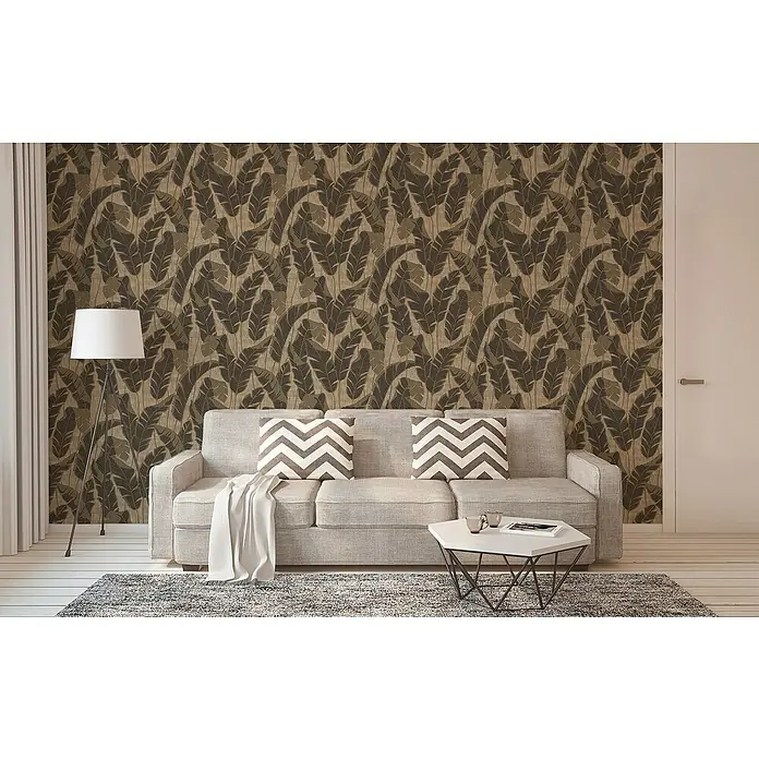 A.S. Création Jade 2 Vliestapete Blätter - Schwarzbeige, Floral, 10,05 x 0,53 m - Einladendes Wohnzimmer mit grauem Sofa, gemusterten Kissen und stilvollem Couchtisch, akzentuiert durch eine elegante Stehlampe.