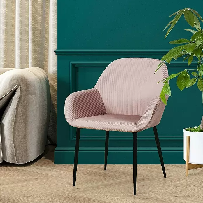 Silla butaca Giulia - Rosa, 2 pzs. - Cómoda silla de terciopelo acanalado rosa con patas negras, colocada en un ambiente de sala de estar moderno.
