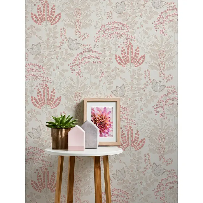 A.S. Création Famous Garden Vliestapete - Weiß-Taupe-Rosa, Floral, 10,05 x 0,53 m - Nahaufnahme eines kleinen Tischs mit einer Sukkulente, Deko-Häusern und einem gerahmten Blumenbild vor einer geblümten Tapete.
