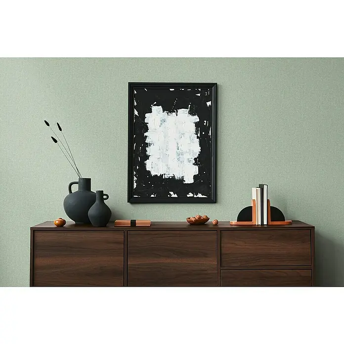 A.S. Création Famous Garden Vliestapete - Grün, Uni, 10,05 x 0,53 m - Stilvolles Interieur mit einer modernen Kommode aus dunklem Holz, dekoriert mit Vasen, Kunst und Buchstützen.