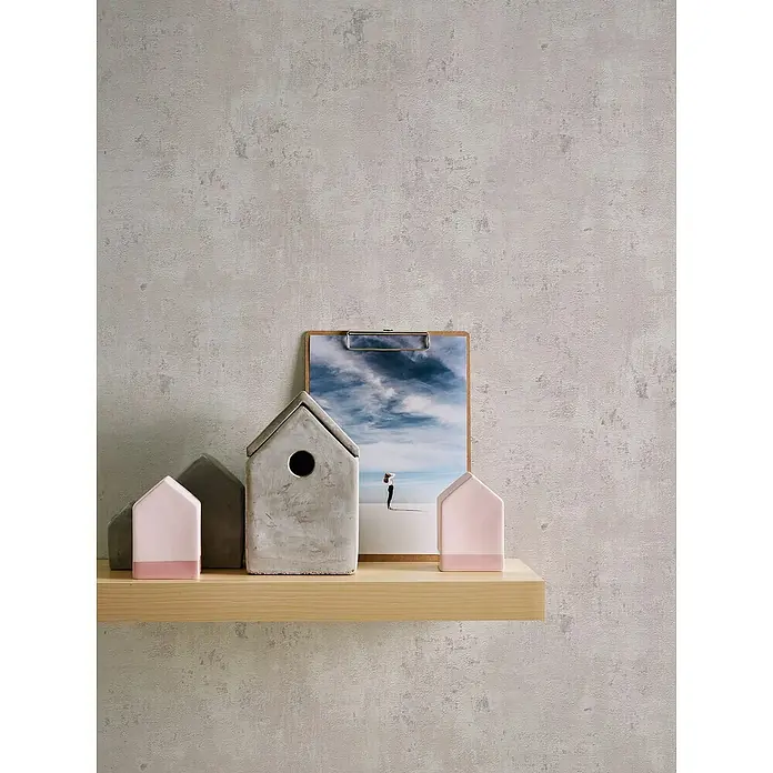 A.S. Création Stories of Life Vliestapete Patina - Weiß-Grau-Silber, Betonoptik, 10,05 x 0,53 m - Eine Nahaufnahme eines Holzregals mit Deko-Häusern aus Beton und Holz, darunter ein Vogelhaus und ein Clipboard mit einem Strandmotiv.