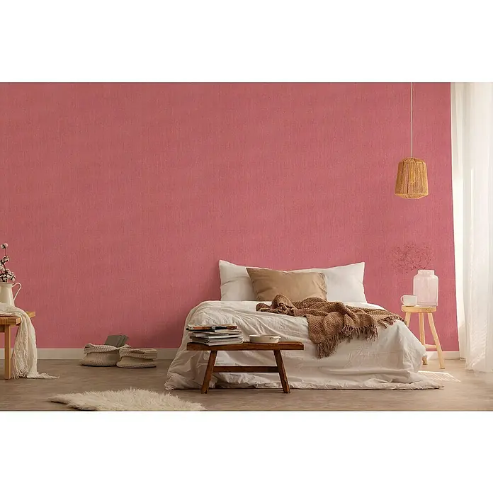 A.S. Création Stories of Life Vliestapete - Rot, Uni, 10,05 x 0,53 m - Schlafzimmer mit Terrakotta-Akzentwand und gemütlicher Einrichtung mit einem rustikalen Nachttisch und einem Lampenschirm aus Korbgeflecht.