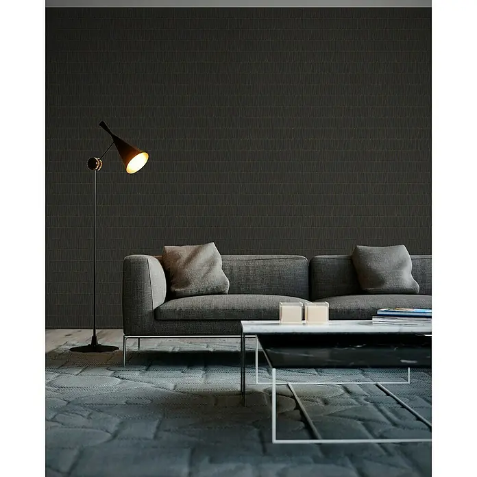 A.S. Création Jade 2 Vliestapete - Schwarz-Gold-Anthrazit, Grafisch, 10,05 x 0,53 m - Elegantes Wohnzimmer mit einem modernen grauen Sofa, einem Marmor-Couchtisch und einer stilvollen Stehlampe. Der graue Teppich rundet das Gesamtbild ab.