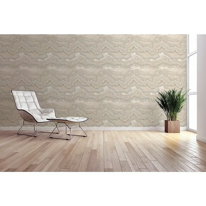 A.S. Création Stories of Life Vliestapete Marmoroptik Metallic-Effekt - Beige-Creme-Silber, Steinoptik, 10,05 x 0,53 m - Stilvolles Interieur mit weißem Sessel und Fußhocker, ergänzt durch eine Zimmerpflanze in einem Holzkübel, vor einer dekorativen Wand mit Marmormuster.