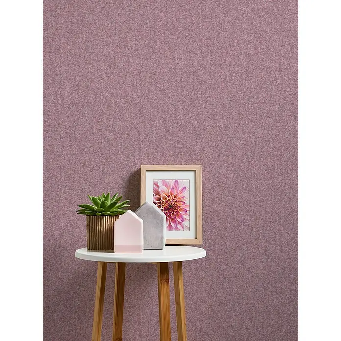 A.S. Création Famous Garden Vliestapete - Violett-Pink, Uni, 10,05 x 0,53 m - Deko-Tisch mit Sukkulente, Hausdeko und Bilderrahmen vor einer lila Wand. Die Objekte sind auf einem kleinen, runden Beistelltisch platziert.