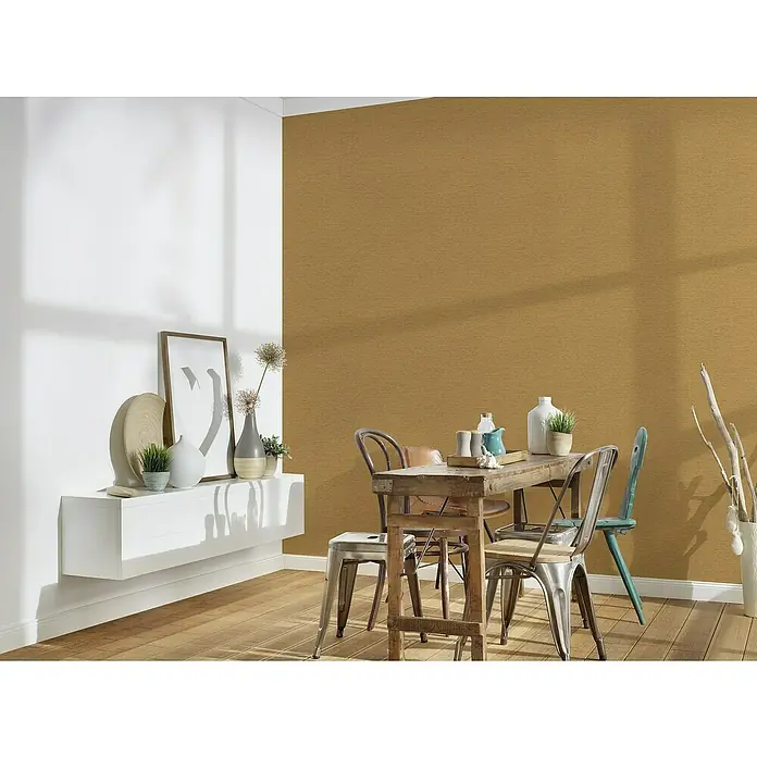 A.S. Création Famous Garden Vliestapete - Goldbraun-Gelb, Uni, 10,05 x 0,53 m - Eine rustikale Essecke mit einem Holztisch und verschiedenen Stühlen, ergänzt durch eine moderne Wandkonsole mit Dekorationsgegenständen.