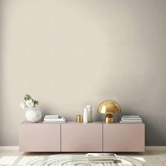 A.S. Création Stories of Life Vliestapete - Sand, Uni, 10,05 x 0,53 m - Elegantes Sideboard in zartem Rosa mit goldenem Lampenschirm und dekorativen Accessoires für ein stilvolles Wohnambiente.