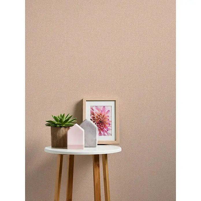 A.S. Création Famous Garden Vliestapete - Orange-Rosa, Uni, 10,05 x 0,53 m - Nahaufnahme eines Beistelltisches mit einer Sukkulente, Deko-Häusern und einem gerahmten Blumenbild, das eine gemütliche Raumatmosphäre schafft.