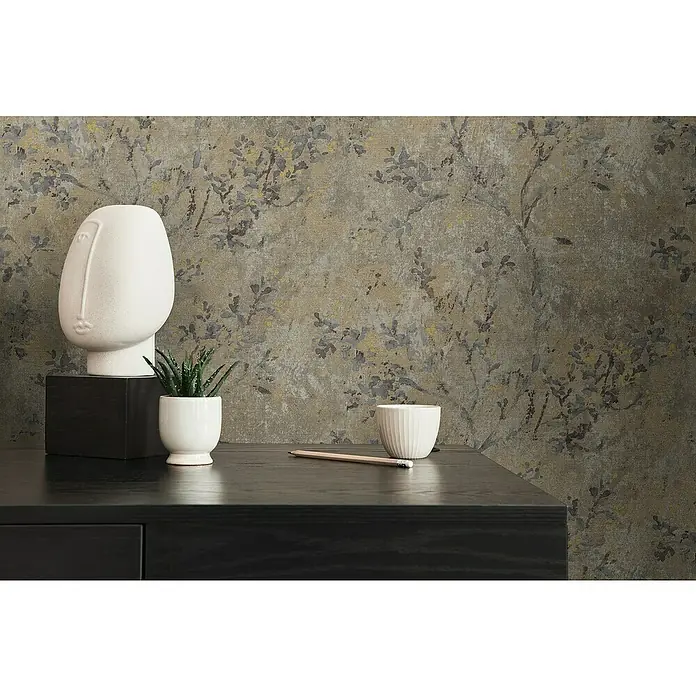 A.S. Création Stories of Life Vliestapete Zweig - Braun-Grau-Gold, Floral, 10,05 x 0,53 m - Nahaufnahme einer modernen Dekoration mit einem Gesicht, einer Pflanze und einem Bleistift auf einem schwarzen Tisch.
